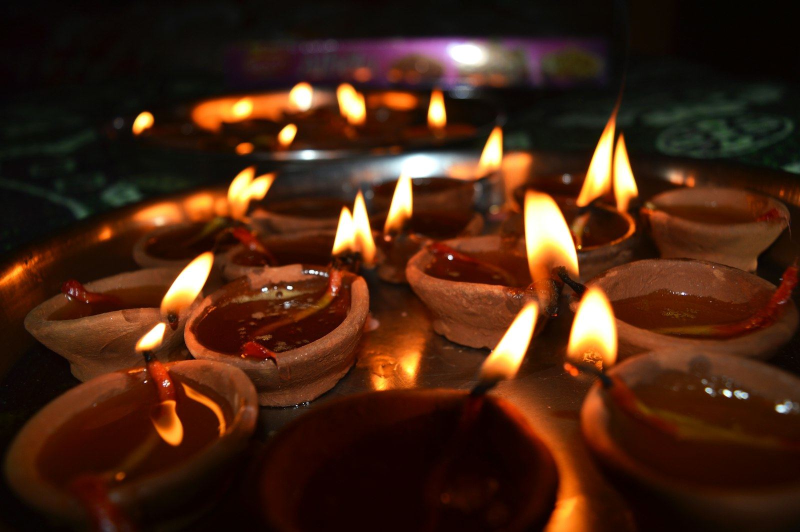 Rows of lit clay diyas at a temple