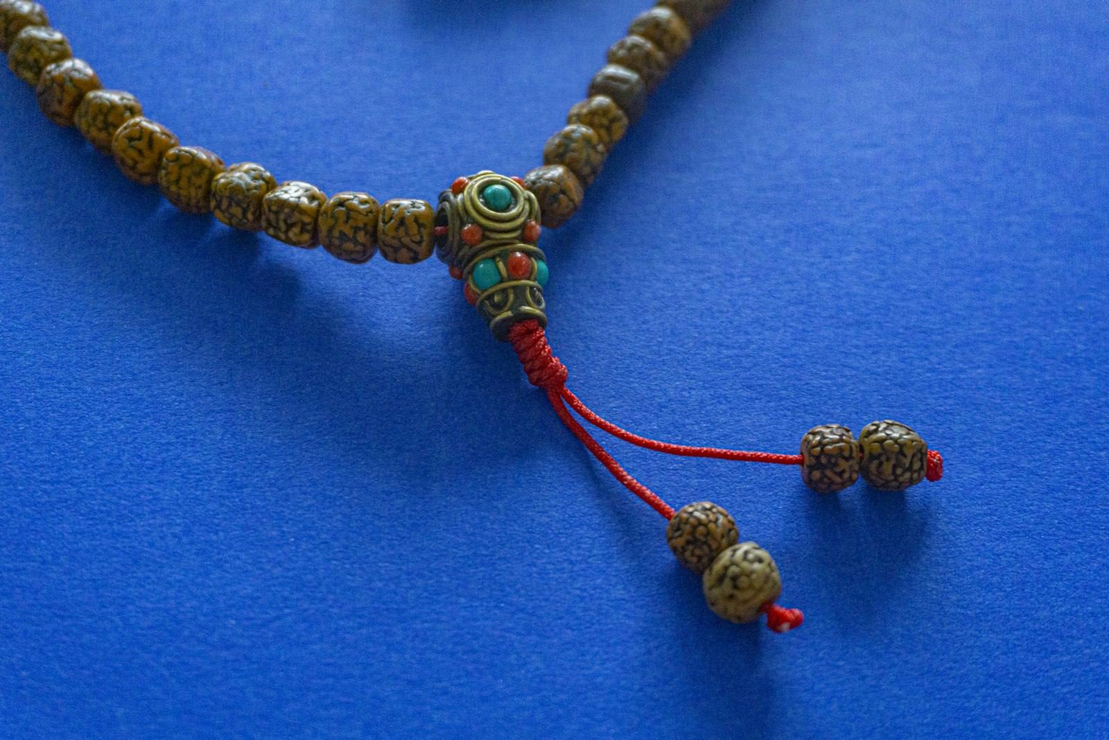 Close-up of a rudraksha mala with red tassel