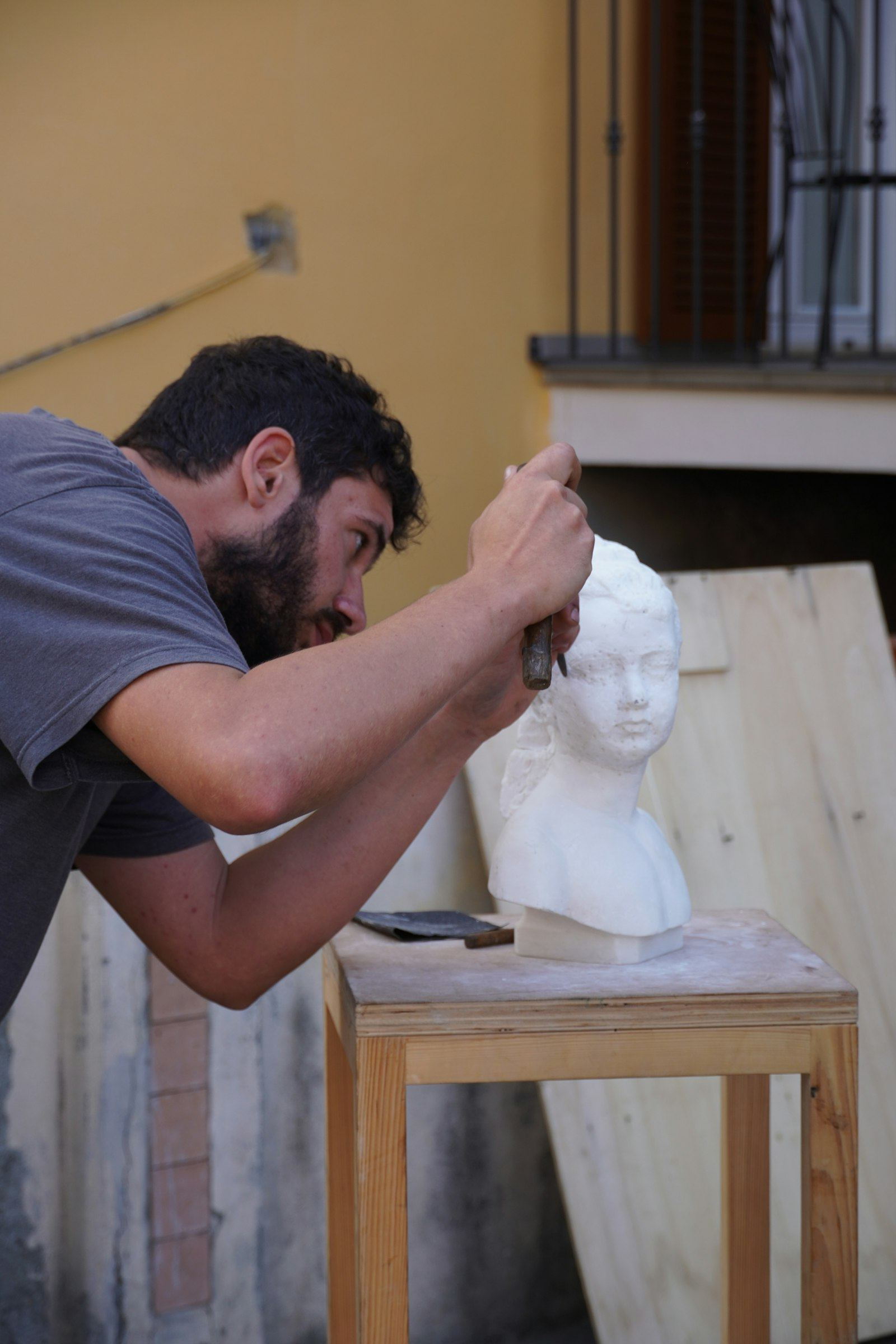 Sculptor hand-carving a marble bust with a chisel