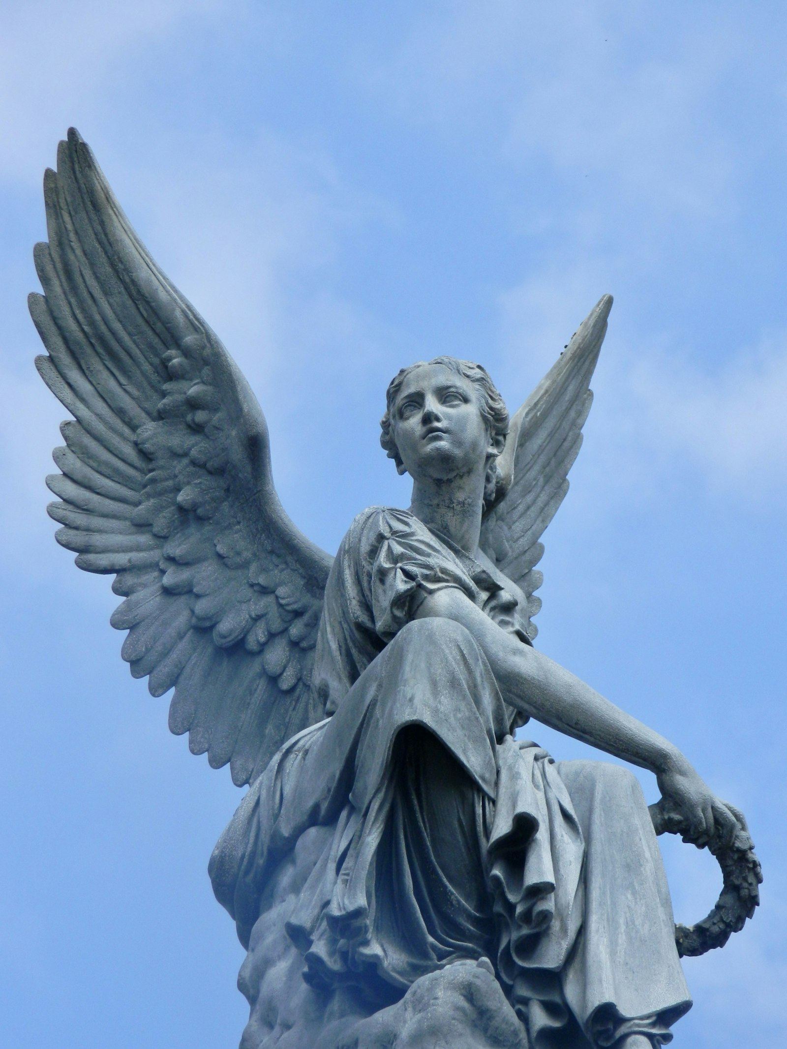 Stone angel statue with raised wings against the sky