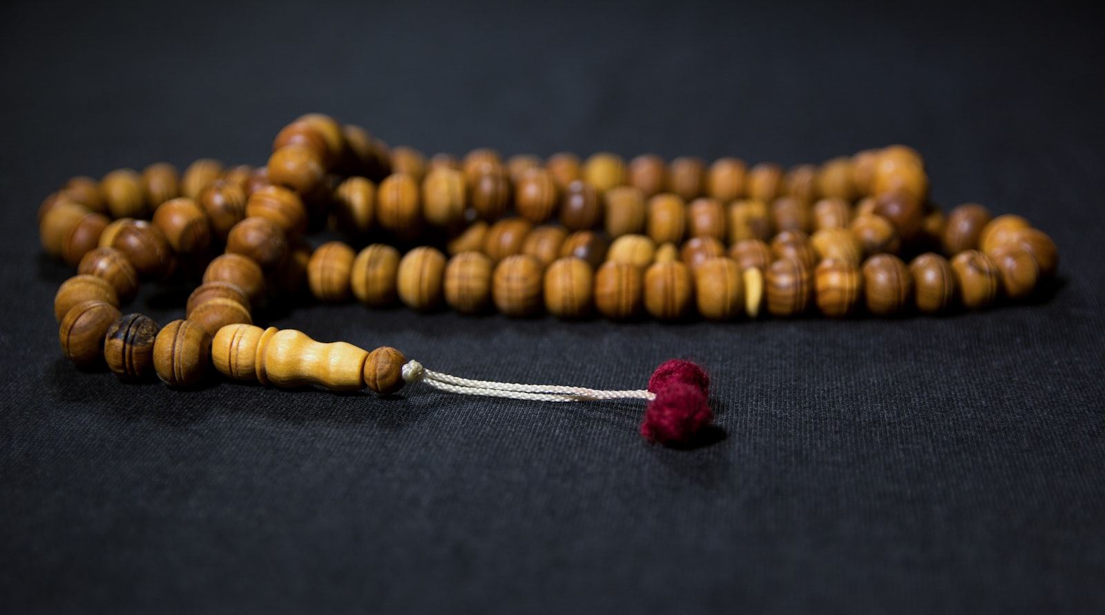 Wooden mala beads with a red tassel on dark wood
